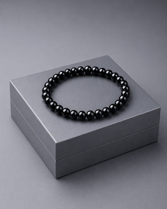 Black beaded bracelet on a gray box against a gray background