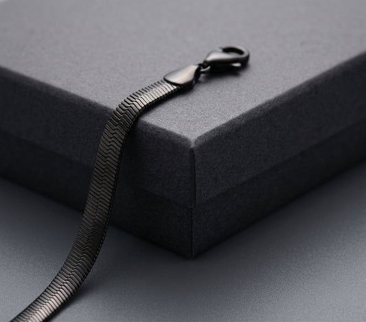 Black snake chain on a grey surface