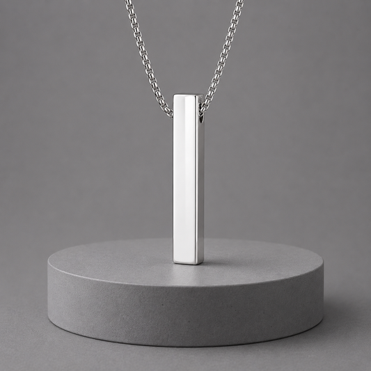 Silver pendant necklace on a grey concrete stand with a grey background