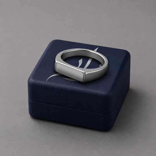 Silver ring on a blue jewelry box against a grey background