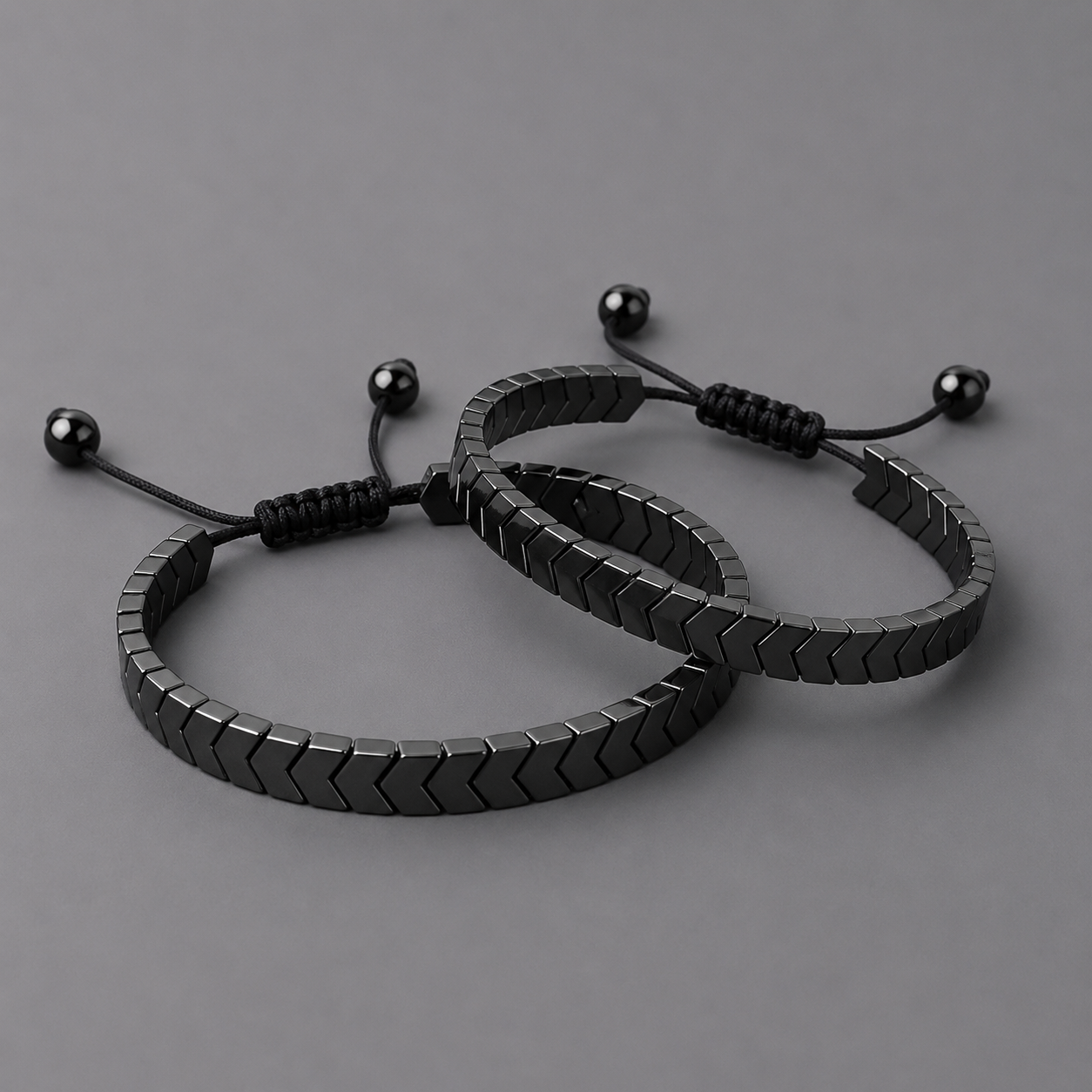 Two black arrow beaded bracelets on a grey background