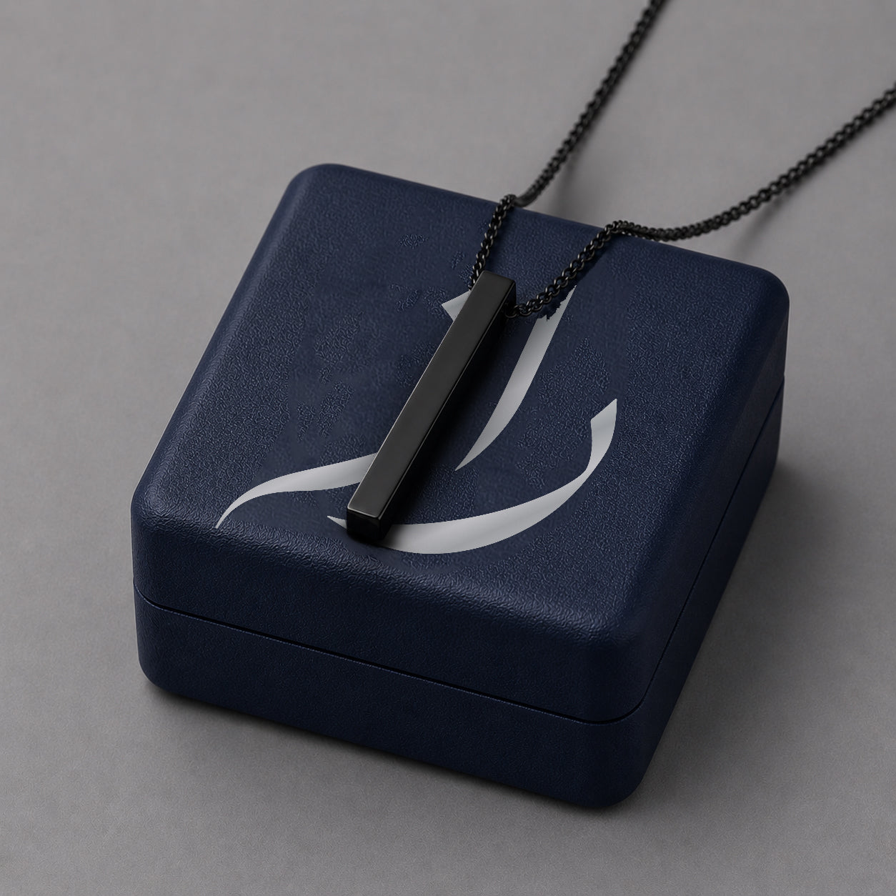 Black pendant over a dark blue jewelry box with a grey background