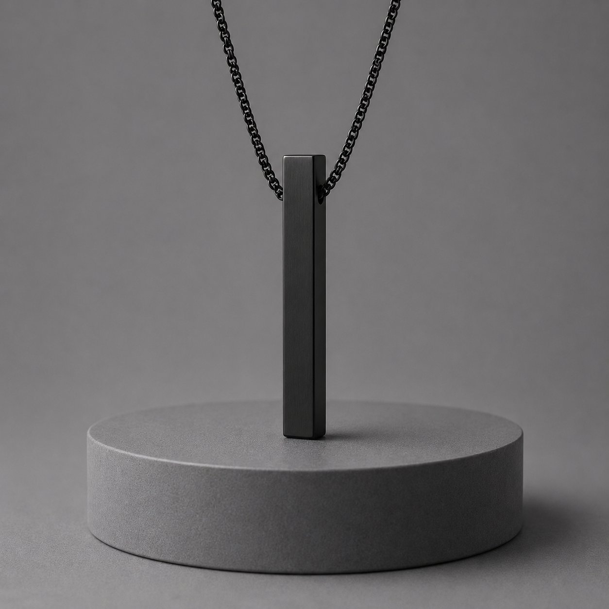 Black pendant necklace on a grey stand against a grey background