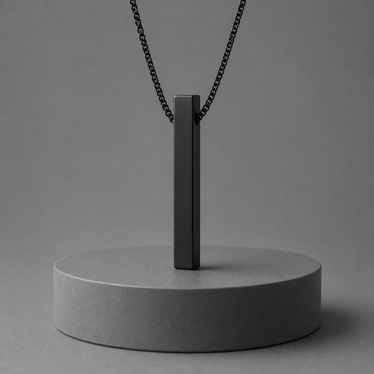 Black pendant necklace on a grey stand against a grey background