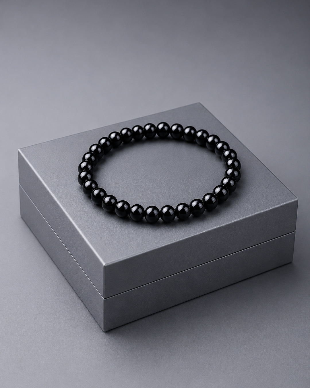Black beaded bracelet on a gray box against a gray background