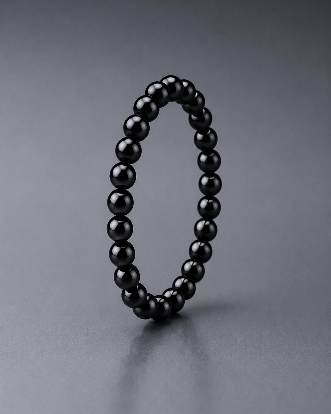 Black beaded bracelet standing on a grey background