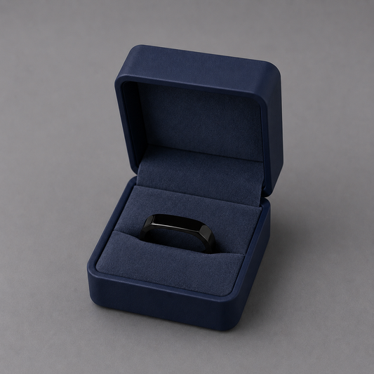 Navy blue jewelry box with a black ring inside on a grey background