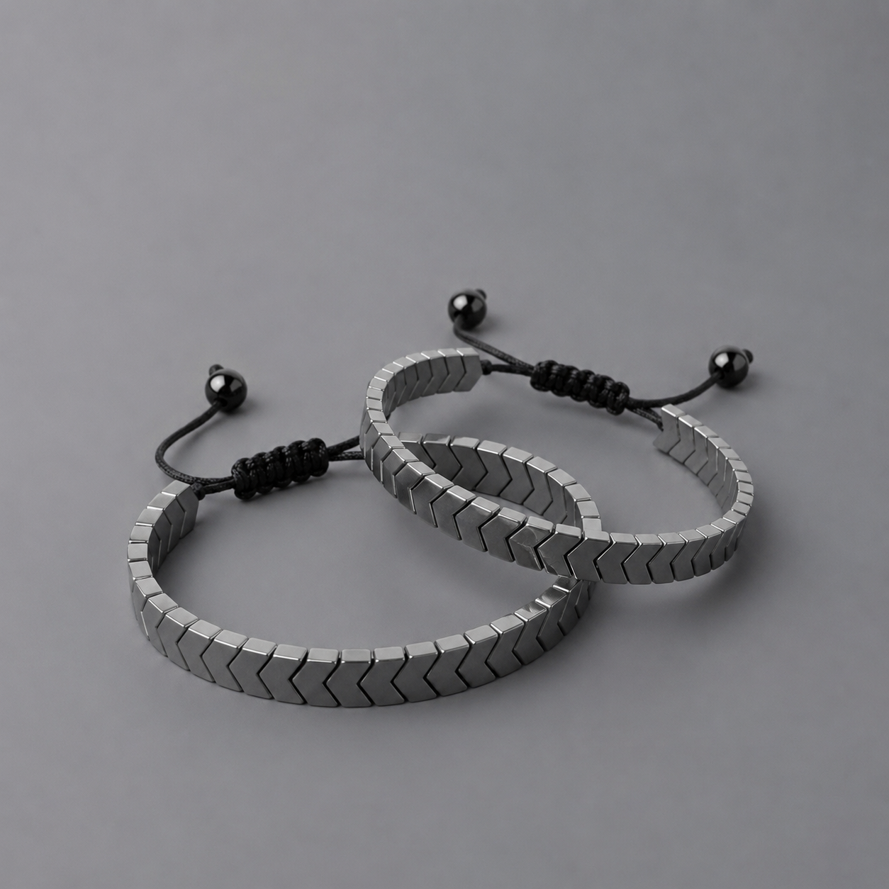 Two silver bracelets with arrows design on a grey background