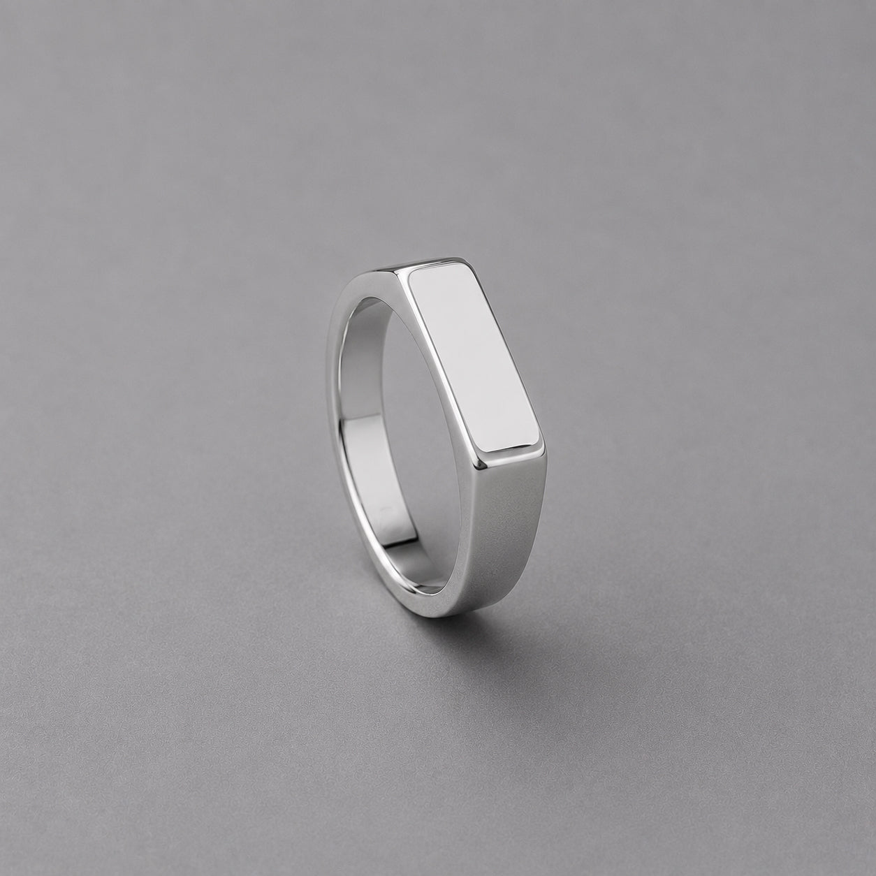 Silver ring with a flat top on a grey background