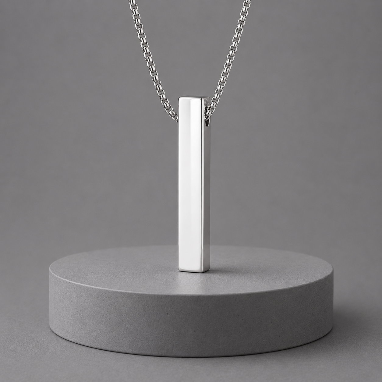 Silver pendant necklace on a grey concrete stand with a grey background