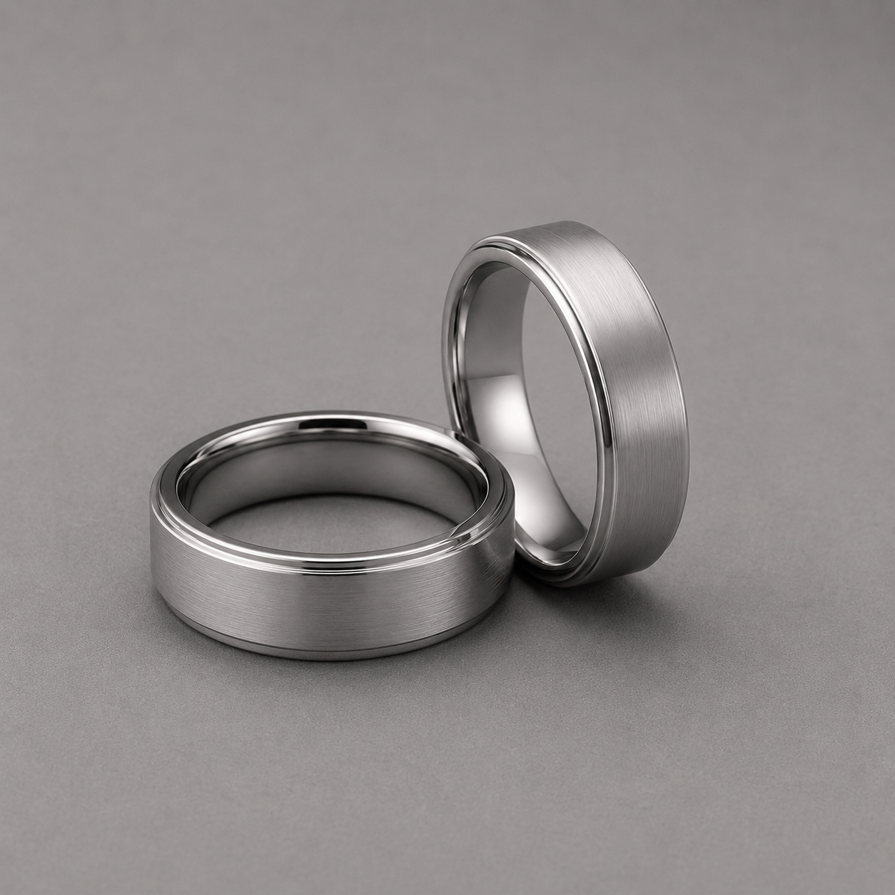 Two silver rings on a grey background
