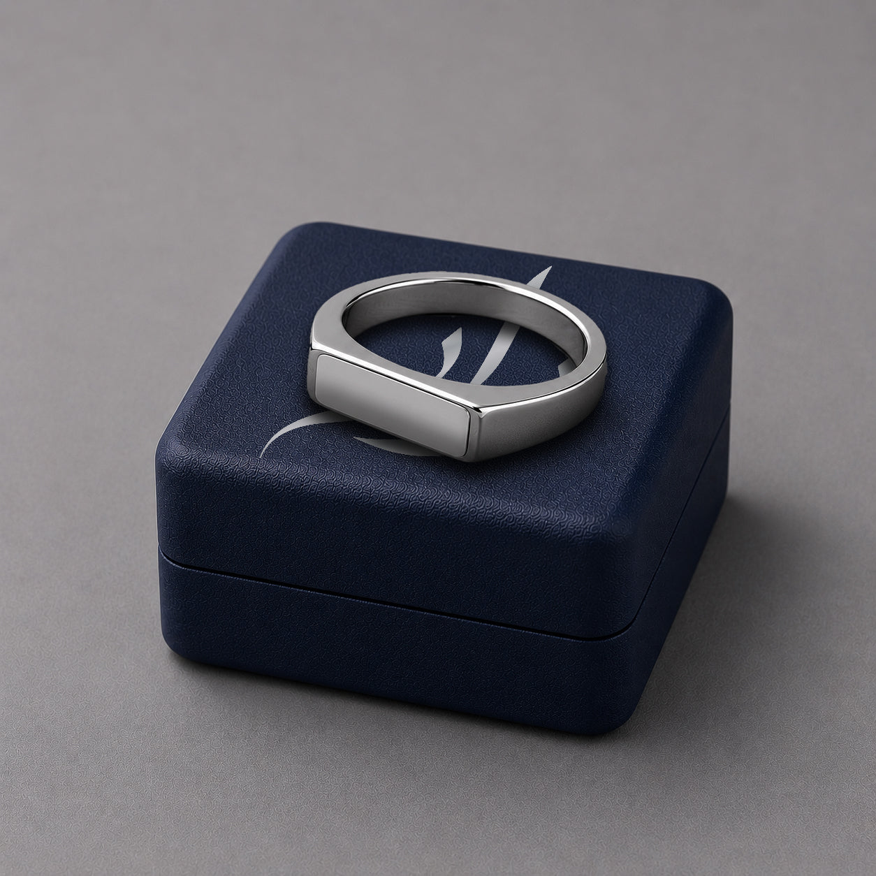Silver ring on a blue jewelry box against a grey background